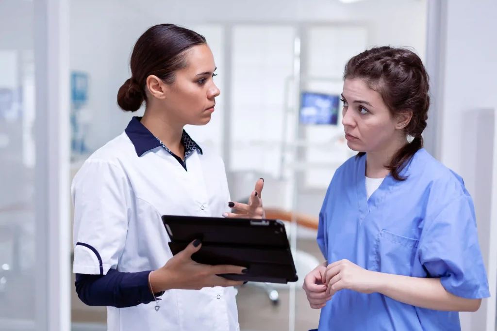 an image of a dentist and dental hygienist discussing personalized hygiene plan for a patient in a dental clinic named Liberty Dentists in Shoreditch, London